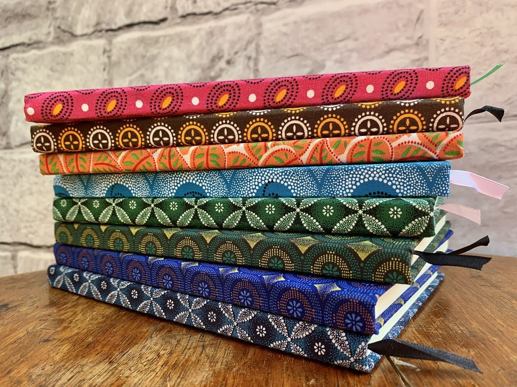 Stak of shwe shwe covered notebooks in different colour fabrics